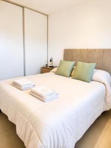 a large white bed with two towels on it at LA RIVIERA María II - CON COCHERA in Villa María