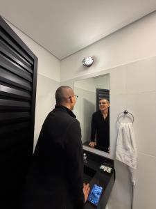 a man looking at his reflection in a mirror at Add Hotéis Mascote in São Paulo
