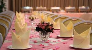 a table with a pink table cloth with a vase of flowers at Cheerful Hotel in Nanhai
