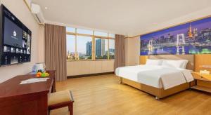 a hotel room with a bed and a desk and a tv at Cheerful Hotel in Nanhai
