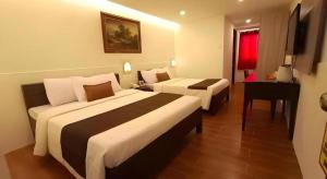 a hotel room with two beds and a desk at Hotel Asuncion in Laoag