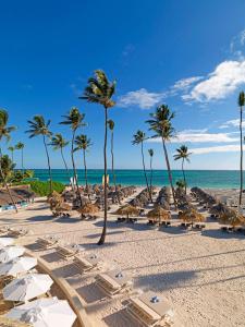 a beach with umbrellas and chairs and palm trees at Paradisus by Meliá Grand Cana - All Suites - All Inclusive in Punta Cana
