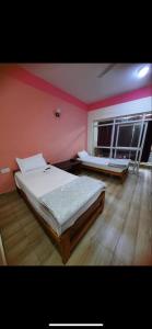 two beds in a room with pink walls and wooden floors at Gelephu city hotel in Geylegphug