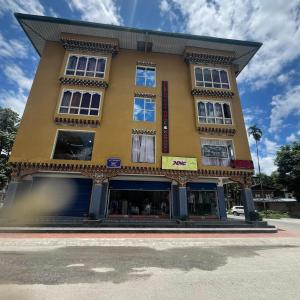 a tall yellow building on the corner of a street at Gelephu city hotel in Geylegphug