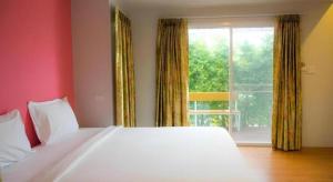 a bedroom with a white bed and a large window at Baan Kula Mahasarakam in Ban Nong Chik