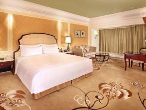 a bedroom with a large bed and a living room at L'Arc Hotel Macau in Macau