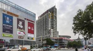 a large building with cars parked in a city at IU Hotel Baoding Goverment Shidai in Baoding
