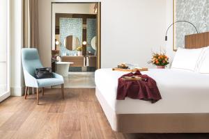 a bedroom with a white bed and a blue chair at Palazzo Cordusio, a Gran Meliá Hotel - The Leading Hotels of the World in Milan