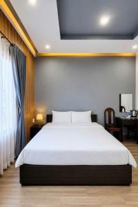 a bedroom with a large white bed and a desk at Lion Homestay Huế in Thôn Lại Thê