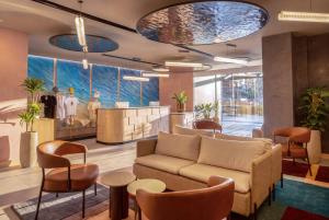 a lobby with a couch and chairs and a counter at INNSiDE by Meliá Bugibba in St. Paul's Bay