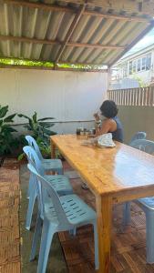 a woman sitting at a wooden table with chairs at Baan Yuan in Prachuap Khiri Khan