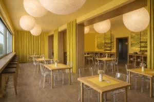 a restaurant with tables and chairs and yellow walls at Hotel Auronzo Dolomites, Affiliated by Melia in Auronzo di Cadore