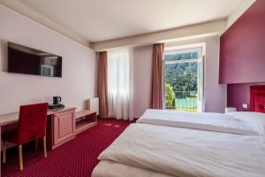 a hotel room with a bed and a desk and a window at Hotel Auronzo Dolomites, Affiliated by Melia in Auronzo di Cadore