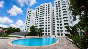 a large white apartment building with a swimming pool at Likas Square - KK Spacious Homestay in Kota Kinabalu
