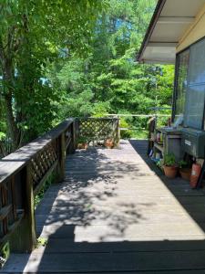 a wooden walkway leading to a house with trees at Guest house AZSINN in Ueda