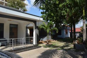 a white house with a porch and a tree at Masaki Comfort III Dar es Salaam Tanzania in Dar es Salaam