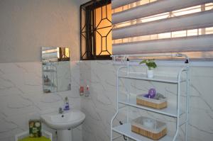 a white bathroom with a sink and a toilet at Masaki Comfort III Dar es Salaam Tanzania in Dar es Salaam +81 photos