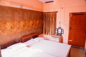 a bedroom with a bed with white sheets and a window at JS Homestay in Nāgercoil