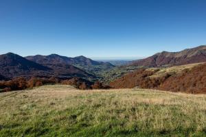 a view of a grassy hill with mountains in the background at Buron du Tournel, un écrin d'exception in Le Lioran