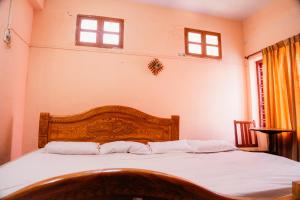 a bedroom with a bed with white sheets and two windows at JS Homestay in Nāgercoil