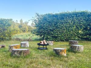 a person laying on a table in a field with tree stump tables at 4 person holiday home in Allingåbro in Allingåbro