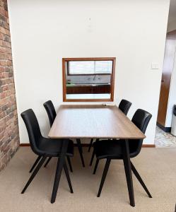 a dining room table with black chairs and a window at Speers Point Serviced Apartments in Cockle Creek