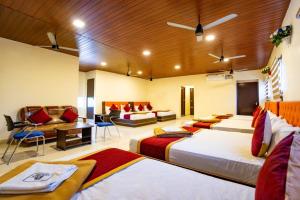a hotel room with three beds and a couch at SREE Kumaran Residence in Rāmeswaram