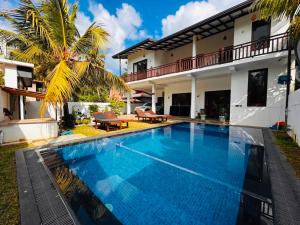 a swimming pool in front of a villa at Parrot Perch Villa Dickwella in Dickwella
