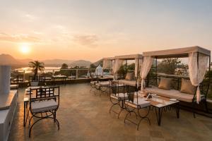 a hotel patio with tables and chairs and the sunset at Raj Kuber - A Boutique Lake View Hotel in Udaipur