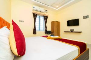 a bedroom with a bed with red pillows and a tv at SREE Kumaran Residence in Rāmeswaram
