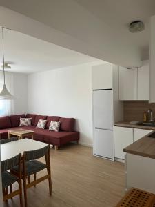 a living room with a red couch and a kitchen at Apartman Raba in Šušanj