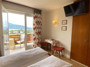 a bedroom with a bed and a table and a balcony at St. Oswalderhof in Pörtschach am Wörthersee
