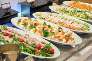 a buffet with many plates of food on a table at Hotel Hokke Club Hiroshima in Hiroshima
