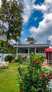 a house with a yard with red flowers in front of it at Kudrat Villa with Private Pool in Dehradun