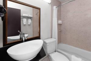 a bathroom with a toilet and a sink and a tub at Travelodge by Wyndham Milwaukee in Milwaukee +57 photos