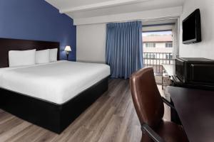 a hotel room with a bed and a television at Travelodge by Wyndham Milwaukee in Milwaukee
