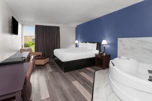 a hotel room with a bed and a tub at Travelodge by Wyndham Milwaukee in Milwaukee