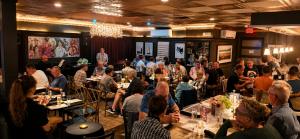 a group of people sitting at tables in a room at Pilgrim House in Provincetown