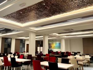 a room filled with tables and chairs with red chairs at J HOTEL in Kampong Kiulap