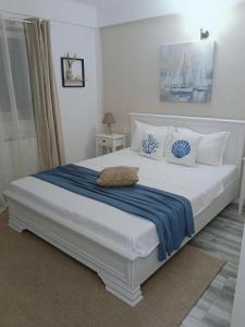 a bedroom with a white bed with a blue blanket at Vila MerSea in Mamaia Sat/Năvodari