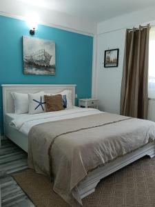 a bedroom with a large bed with a blue wall at Vila MerSea in Mamaia Sat/Năvodari