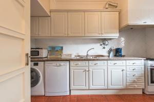 a kitchen with white cabinets and a washer and dryer at The Ideal Place close to the Castle in Lisbon