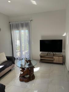a living room with a tv and a glass table at Eleonora apartment in Porto Rafti