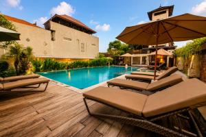 a swimming pool with two lounge chairs and an umbrella at Bali Ayu Hotel & Villas 10 Minutes Walking Distance to the Beach in Seminyak