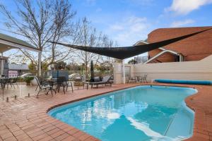 a swimming pool on a patio with chairs and a table at Comfort Inn Lady Augusta in Swan Hill