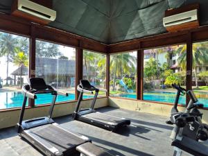 a gym with two treadmills and a swimming pool at Sand & Sandals Desaru Beach Resort & Spa in Desaru