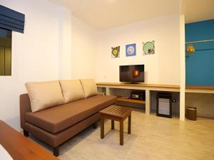 a living room with a couch and a tv at Thalassa Hotel in Ko Tao