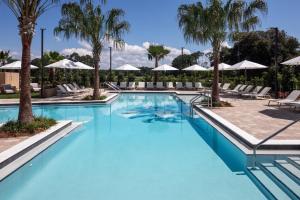 a large swimming pool with palm trees and lounge chairs at Hyatt House Destin in Destin