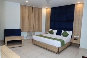 a bedroom with a large bed and a chair at Hotel New JMK in Katra