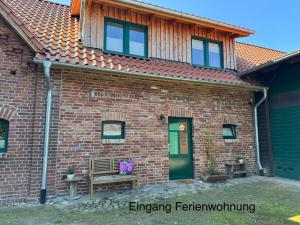 a brick house with a bench and a green door at Brokeloh - Hier bin ich zuhause ! in Landesbergen